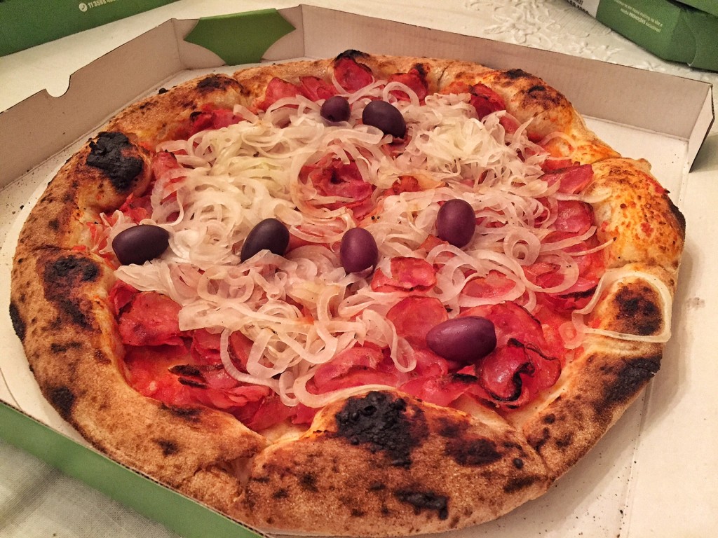 Pizza Calabresa: Generosa porção da calabresa artesanal produzida pela tradicionalíssima Salumeria Cinque coberta por adocicadas e crocantes fatias de cebola e azeitonas pretas (R$55)